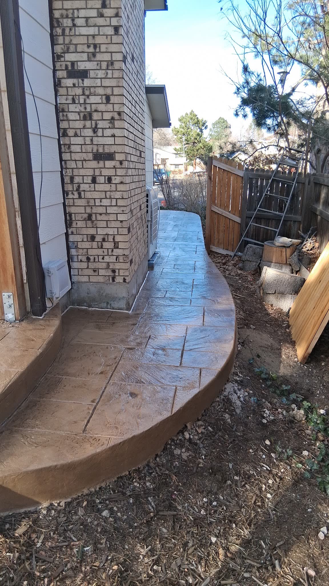 Curved stamped concrete walkway wrapping a brick chimney