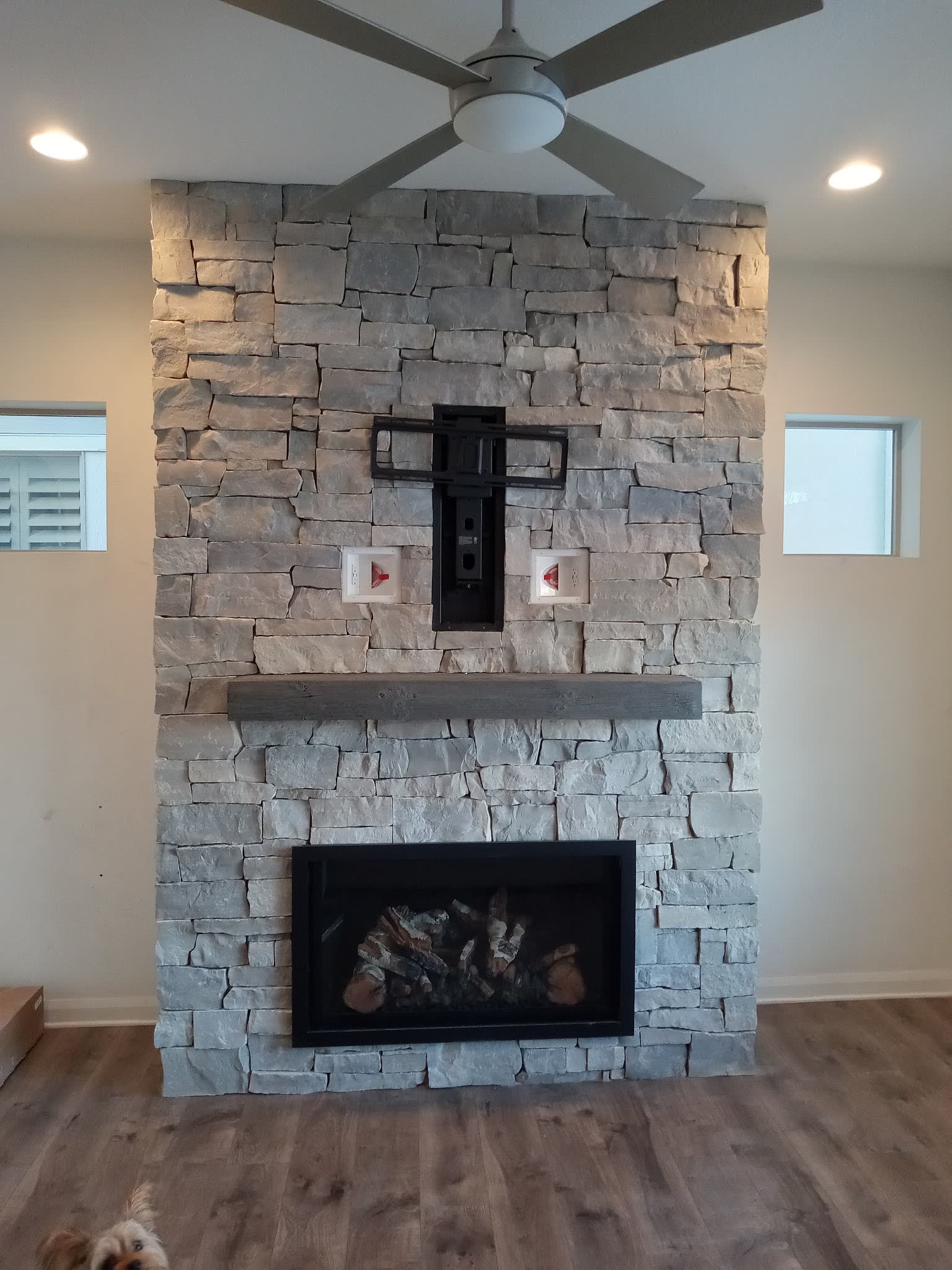 The finished floor to ceiling stacked stone fireplace with a timber mantel