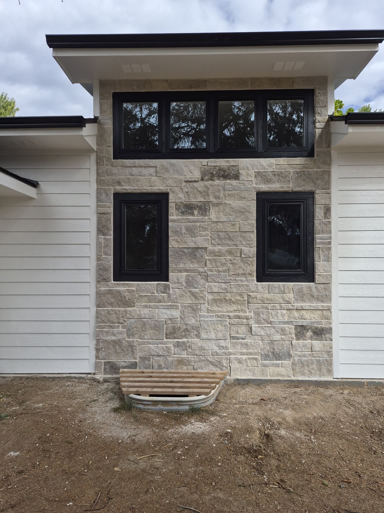 Cut limestone facade laid around black framed windows on a new house