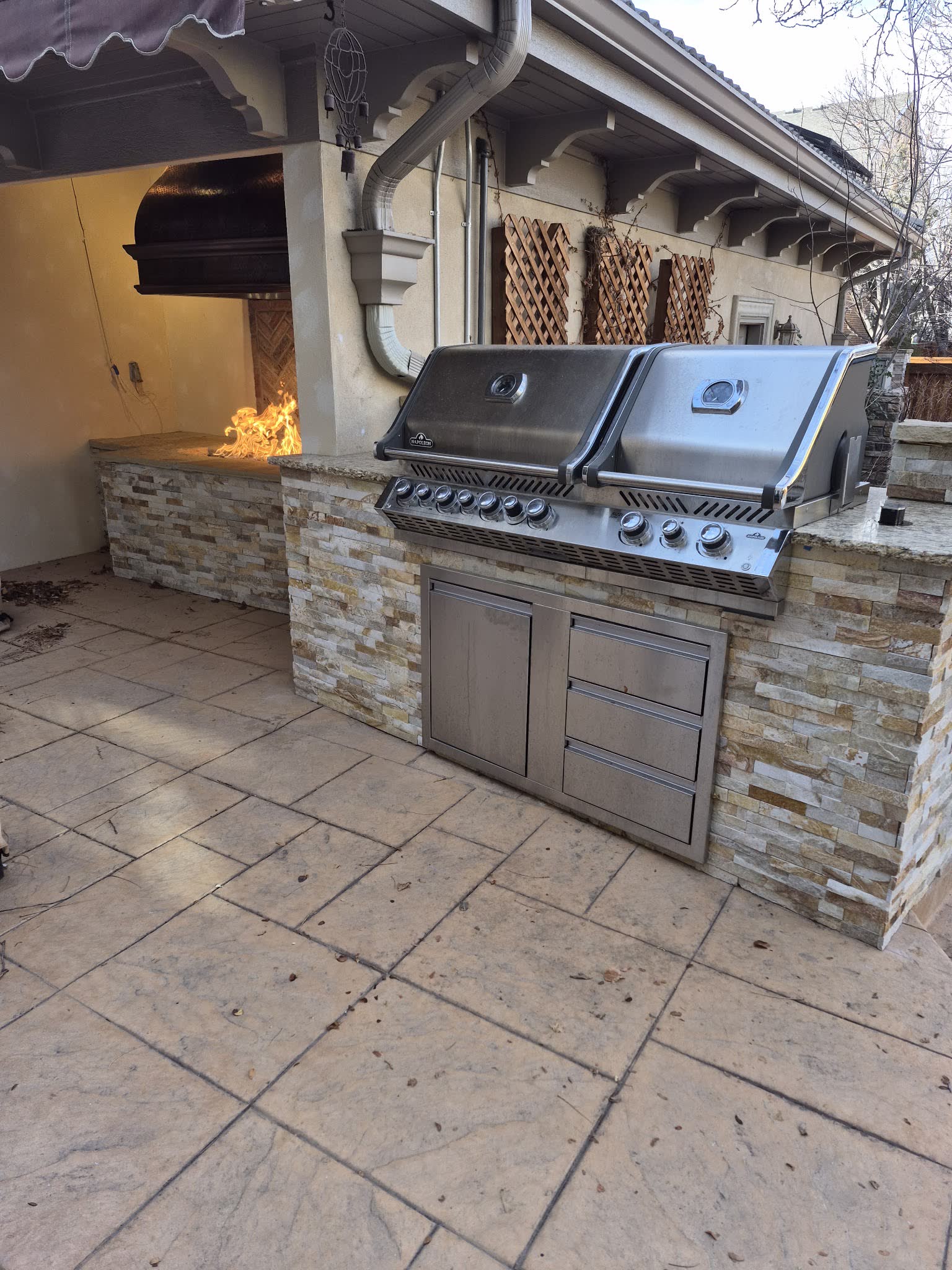Outdoor kitchen with twin grills and a lit stone fire feature